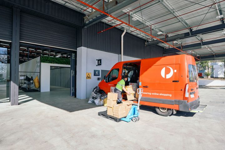 Courier driver loading parcels into van in loading dock